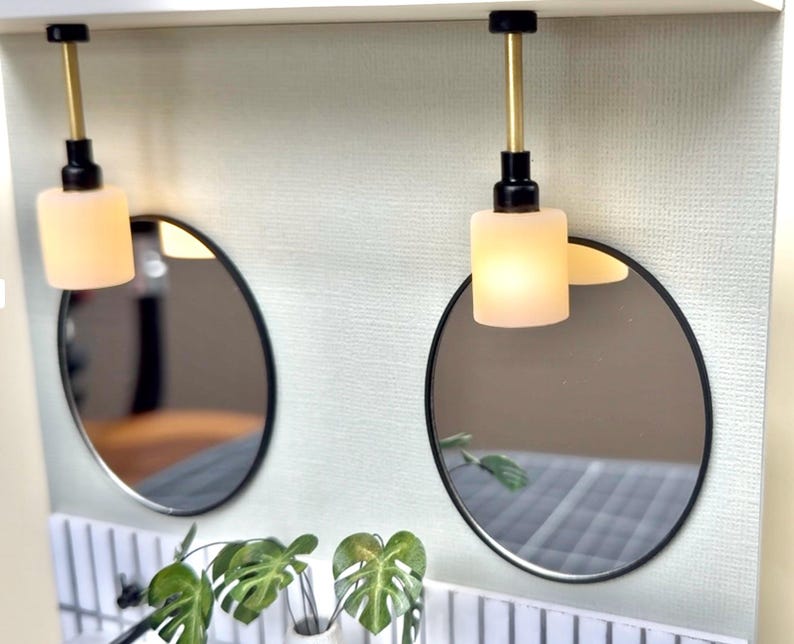 Oval mirrors mounted on green dollhouse wall with pendant lights